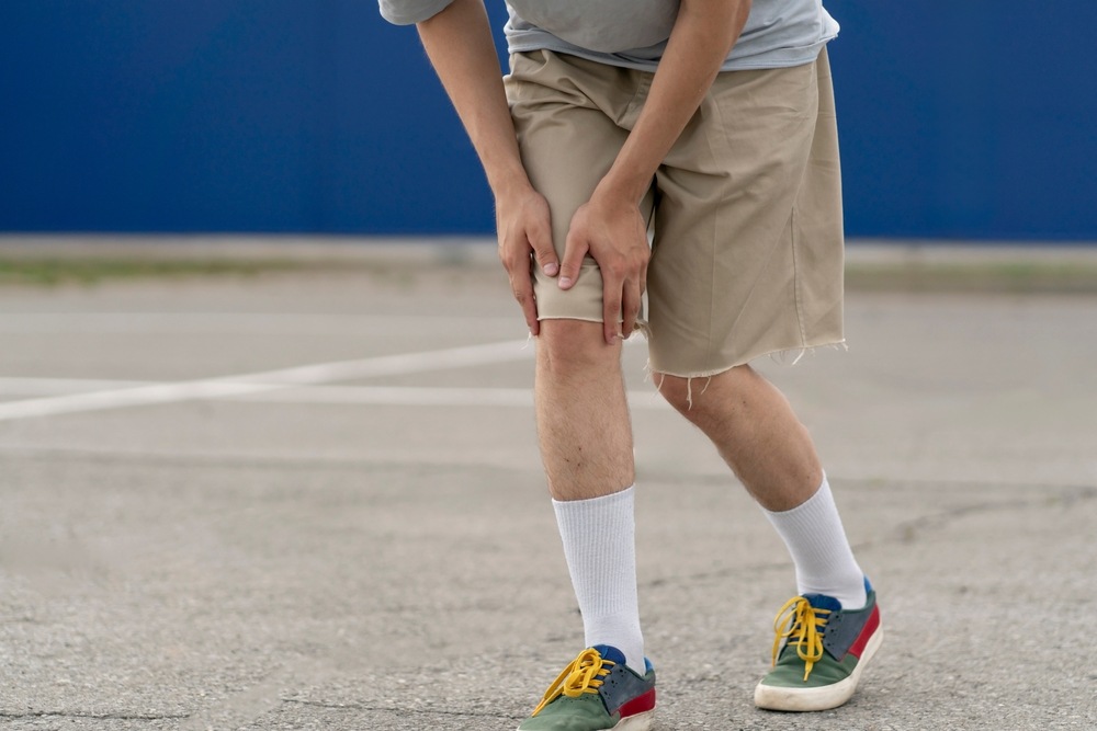 Person standing on a parking lot holding their injured knee after a slip and fall accident, the type of injury a Florida slip and fall lawyer can help with