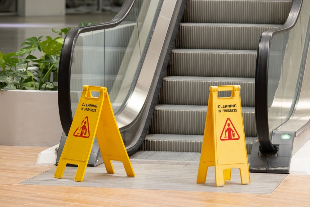 Two yellow caution signs placed near an escalator warning of cleaning in progress, illustrating a property owner's duty of care in a Florida slip and fall claim