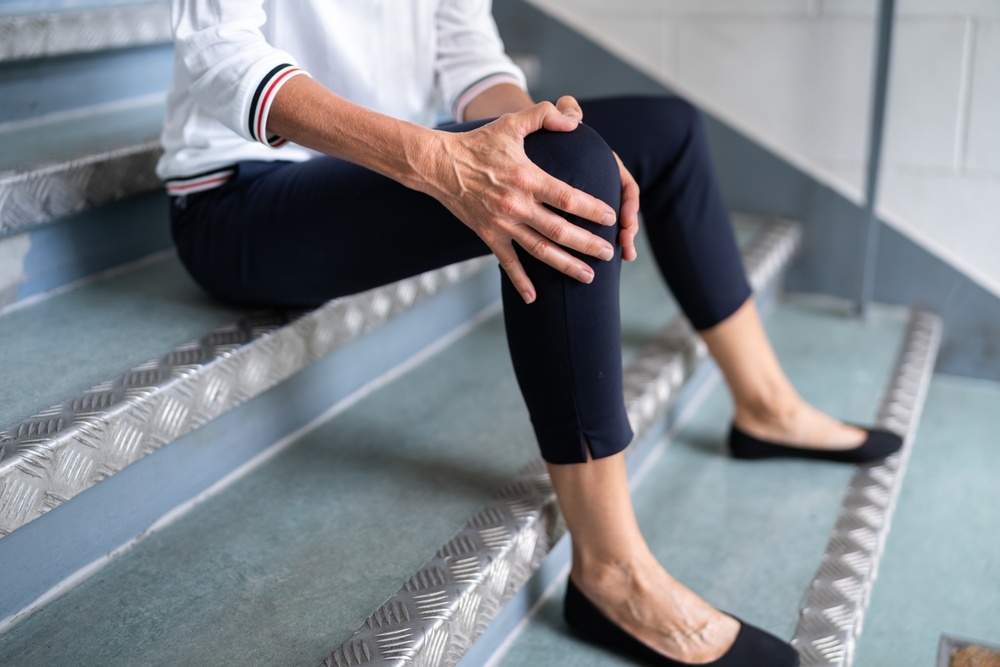 Injured person sitting on stairs holding their knee after a fall, representing the type of injury handled by a slip and fall lawyer in Florida